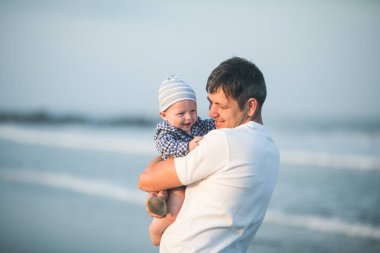 Babalar Günün kutlu olsun. Baba ve bebek kumsalda oynuyorlar. Baba ve çocuk birlikte gün batımının tadını çıkarıyorlar. Sevgi dolu bekar baba, sevimli küçük oğluna sarılıyor..