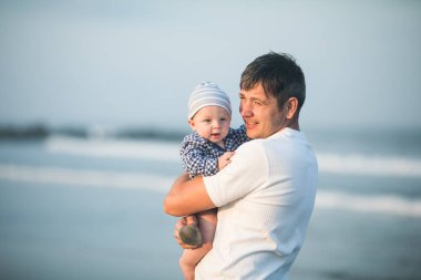 Babalar Günün kutlu olsun. Baba ve bebek kumsalda oynuyorlar. Baba ve çocuk birlikte gün batımının tadını çıkarıyorlar. Sevgi dolu bekar baba, sevimli küçük oğluna sarılıyor..