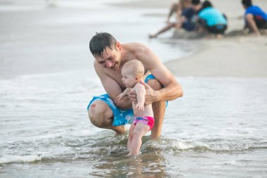 Baba ve bebek okyanusta yüzüyor. Baba ve çocuk birlikte gün batımının tadını çıkarıyorlar. Sevgi dolu bekar baba, sevimli küçük oğluna sarılıyor..