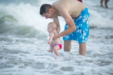 Baba ve bebek okyanusta yüzüyor. Baba ve çocuk birlikte gün batımının tadını çıkarıyorlar. Sevgi dolu bekar baba, sevimli küçük oğluna sarılıyor..
