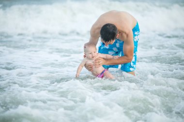 Baba ve bebek okyanusta yüzüyor. Baba ve çocuk birlikte gün batımının tadını çıkarıyorlar. Sevgi dolu bekar baba, sevimli küçük oğluna sarılıyor..