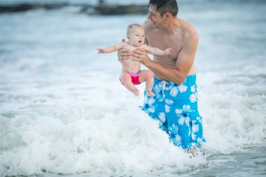 Baba ve bebek okyanusta yüzüyor. Baba ve çocuk birlikte gün batımının tadını çıkarıyorlar. Sevgi dolu bekar baba, sevimli küçük oğluna sarılıyor..
