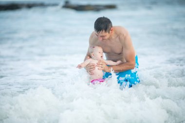 Baba ve bebek okyanusta yüzüyor. Baba ve çocuk birlikte gün batımının tadını çıkarıyorlar. Sevgi dolu bekar baba, sevimli küçük oğluna sarılıyor..