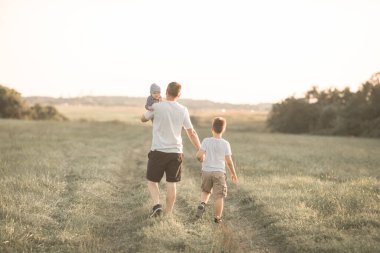 Çocuklarla eğlenmek, babalar ve oğullar için zaman ayırmak, aile aktiviteleri. Baba ve bebek güneşli bir yaz gününde ormanda yürüyorlar. Baba oğlunun elini tutuyor ve onlar oynaşıyorlar.