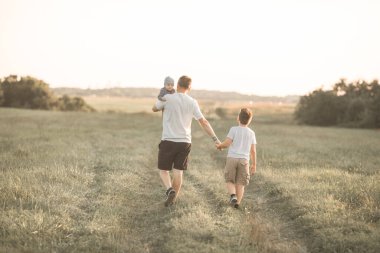 Çocuklarla eğlenmek, babalar ve oğullar için zaman ayırmak, aile aktiviteleri. Baba ve bebek güneşli bir yaz gününde ormanda yürüyorlar. Baba oğlunun elini tutuyor ve onlar oynaşıyorlar.