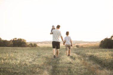 Çocuklarla eğlenmek, babalar ve oğullar için zaman ayırmak, aile aktiviteleri. Baba ve bebek güneşli bir yaz gününde ormanda yürüyorlar. Baba oğlunun elini tutuyor ve onlar oynaşıyorlar.