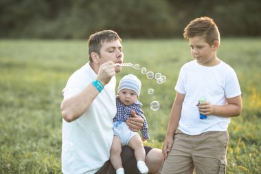 Sahada mutlu bir aile. Oyun oynayıp baloncuk üflüyorlar..