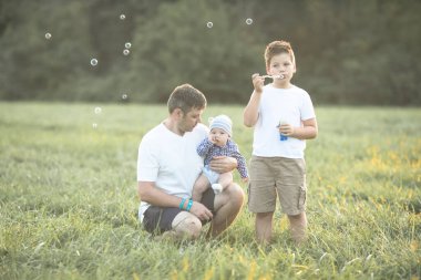 Sahada mutlu bir aile. Oyun oynayıp baloncuk üflüyorlar..