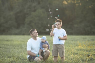 Sahada mutlu bir aile. Oyun oynayıp baloncuk üflüyorlar..