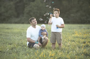 Sahada mutlu bir aile. Oyun oynayıp baloncuk üflüyorlar..