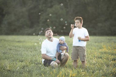 Sahada mutlu bir aile. Oyun oynayıp baloncuk üflüyorlar..