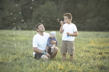 Sahada mutlu bir aile. Oyun oynayıp baloncuk üflüyorlar..