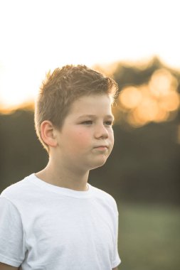 Üzgün küçük Amerikalı çocuk dışarıda kafası karışmış bir şekilde kameraya bakıyor. Kafkas anaokulu öğrencisinin kafası karıştı..