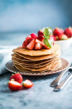 Beyaz tabakta servis edilen taze yaban mersinli, ahududulu ve ballı Amerikan gözlemeleri. Krep ve sütle sağlıklı bir sabah kahvaltısı.