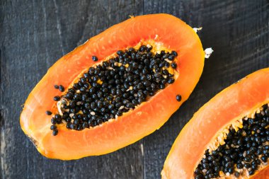 Tam papaya meyvesi ve yarısı ahşap kaplamalı.