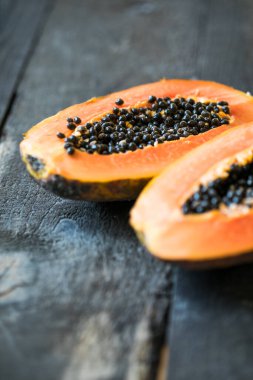 Tam papaya meyvesi ve yarısı ahşap kaplamalı.