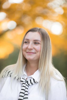 Sonbahar yapraklarını güz doğasında yüzüne tutan mutlu kadın. Sonbahar akçaağaç yapraklı genç bir kadının portresi..