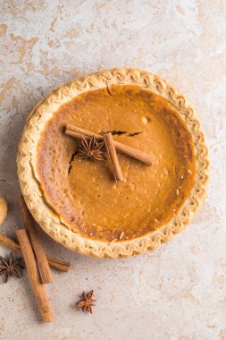 Kahverengi ahşap bir masada taze pişmiş balkabağı turtası. Balkabağı turtası dünya çapında tatillerde ve özel etkinliklerde kullanılıyor..