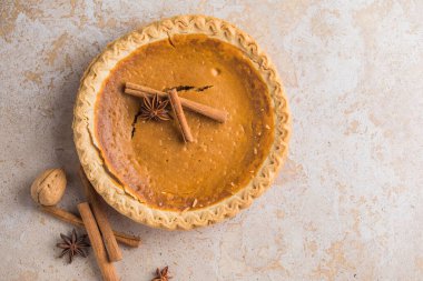 Kahverengi ahşap bir masada taze pişmiş balkabağı turtası. Balkabağı turtası dünya çapında tatillerde ve özel etkinliklerde kullanılıyor..