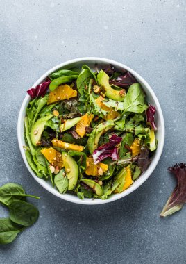 Taze salata organik avokado ve beyaz tabakta portakal ve zeytinyağlı ıspanak yaprakları. vejetaryen yemeği.