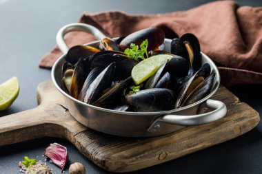 Deniz ürünleri. Kabuklu midye. Fırınlanmış midyeler dökme demir siyah tabakta