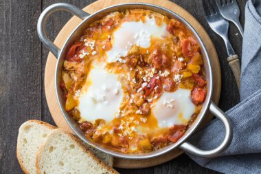 Yumurtalı Shakshuka domates ve maydanozlu dökme demir tavada..