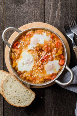Yumurtalı Shakshuka domates ve maydanozlu dökme demir tavada..