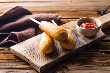 Sosisli sandviç mi, ketçaplı sosis mi? Ahşap bir arkaplan üzerinde üst görünüm tablo sahnesi.