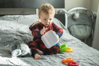 Elinde oyuncaklar ve piramitlerle şaşırmış bir çocuk.