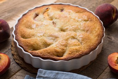 Mutfaktaki ahşap masada ev yapımı şeftali turtası yemek kitabı, toz şeker ve şeftali.