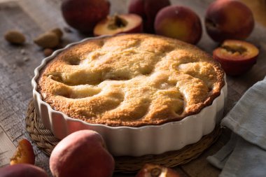 Mutfaktaki ahşap masada ev yapımı şeftali turtası yemek kitabı, toz şeker ve şeftali.