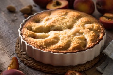Mutfaktaki ahşap masada ev yapımı şeftali turtası yemek kitabı, toz şeker ve şeftali.