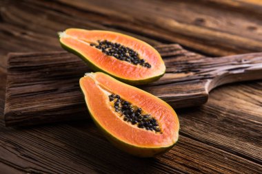 Olgun bir papaya, tahta bir kütükte ikiye bölünmüş..