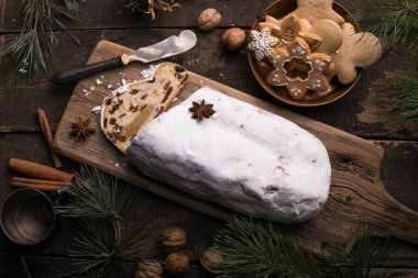 Ahşap arka planda Noel çalıntısı. Geleneksel yılbaşı Alman tatlıları parçalara ayrılmış. Fındıklı kek, badem ezmeli kuru üzüm ve kesme tahtasında kurutulmuş meyve. Xmas için pişirme