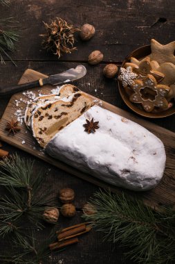 Ahşap arka planda Noel çalıntısı. Geleneksel yılbaşı Alman tatlıları parçalara ayrılmış. Fındıklı kek, badem ezmeli kuru üzüm ve kesme tahtasında kurutulmuş meyve. Xmas için pişirme