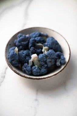 Mavi arka planda pamuk havluları beyazlattıktan sonra elek içinde Mavi Karnabahar