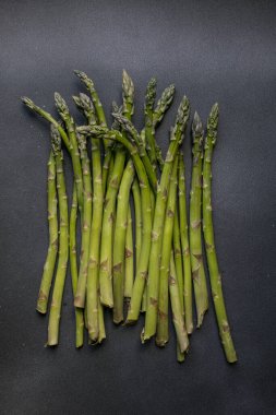 Koyu arka plan üzerinde taze yeşil kuşkonmaz