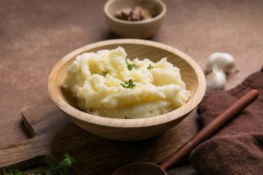 Tahta masadaki ahşap bir kasede servis edilen taze kekik ile kremalı patates püresi..