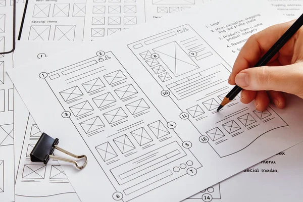 Web design project concept. Close up photo of a UX designer working on website project with a large number of wireframe sketches.