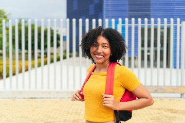 Parkta sırt çantalı gülümseyen kadın.