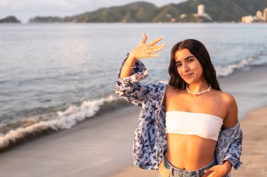 Gün batımında kumsalda poz veren esmer kadın..