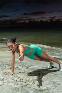 Sahilde şınav çeken Afro bir kadın..