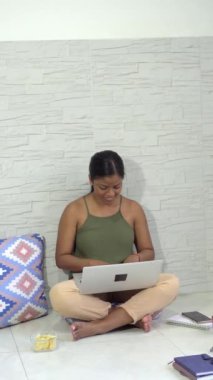 Evde çalışan dizüstü bilgisayarı olan genç bir kadın.