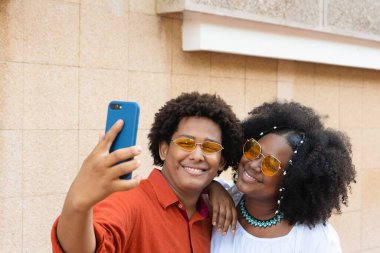 Friends with afro hair taking selfies in the city street