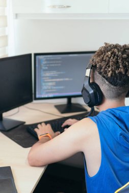 Computer programmer sitting at desk and typing on computer keyboard while creating code while working at home.