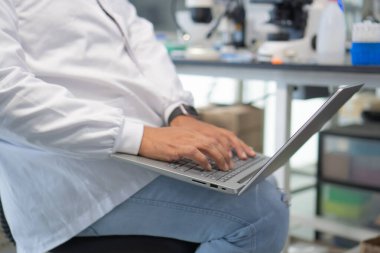Close-up of man in Lab Coat Using Laptop Computer in Lab.