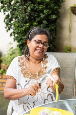 Elderly woman cutting vegetables to prepare dinner.