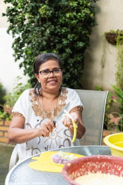 Portrait of an elderly woman cutting vegetables to prepare dinner.