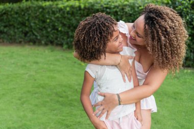 Happy mother and daughter smiling and hugging in the open air.