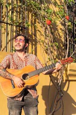 Latin adam sokakta gitar çalıyor.